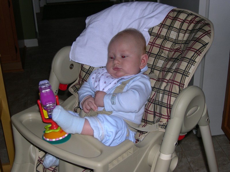 Nicky kicks the toy in his high chair