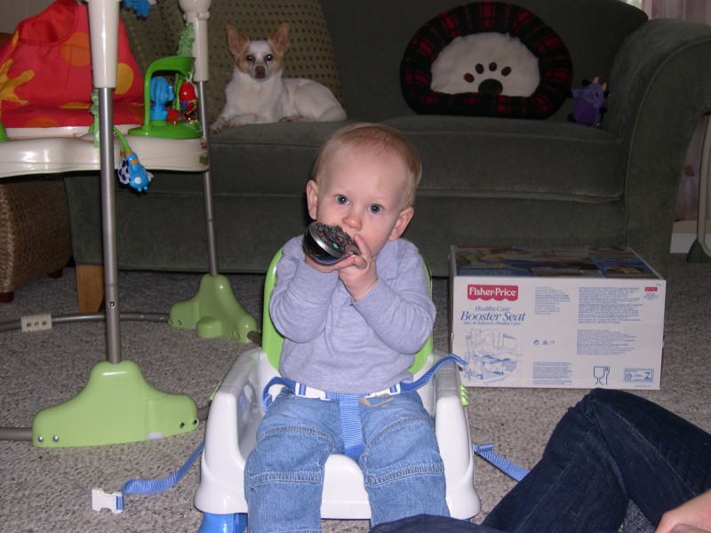 Nicky sitting in his new booster seat with the remote control