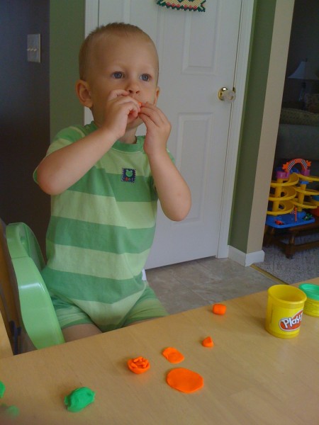 Nicky pretending to eat the hot dog that Mommy made out of Play-Doh