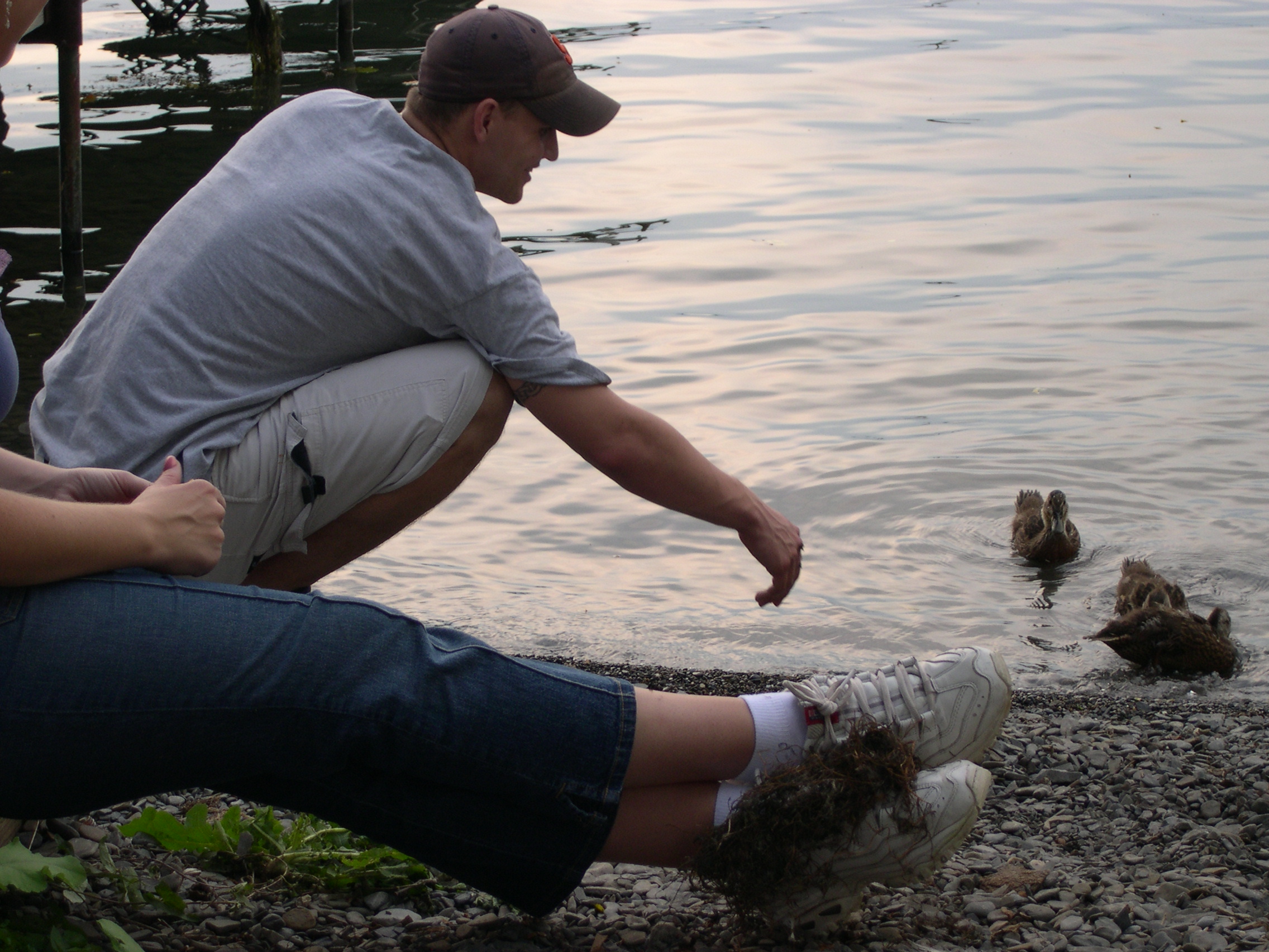 Kevin feeding the ducks and Jessica with something on her shoes